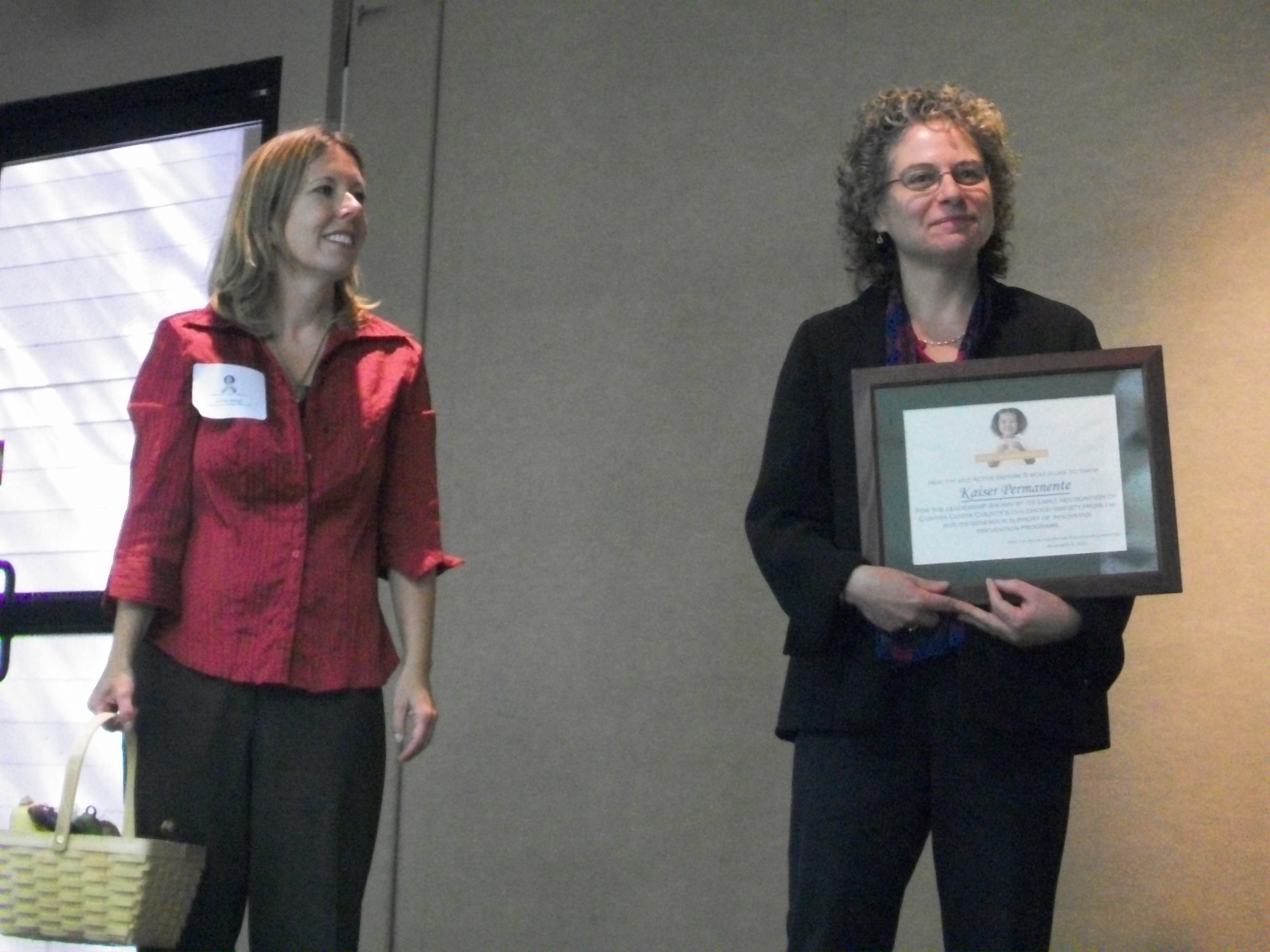 Program Manager Jean Nudelman stands next to Jean Nudelman who accepts the award on behalf of Kaiser Permanente